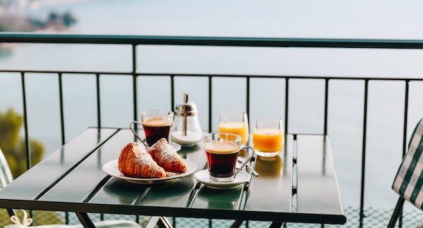 Deliziosa colazione con pasticceria, caffè e succo d'arancia serviti sul balcone con vista mare in Italia.