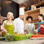Lezione di cucina, concetto culinario, di cibo e di persone - gruppo felice con uno chef maschile che cucina e parla in scuole di cucina