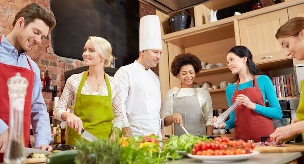 Lezione di cucina, concetto culinario, di cibo e di persone - gruppo felice con uno chef maschile che cucina e parla in scuole di cucina