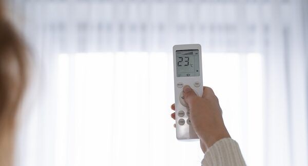 Donna che tiene in mano un telecomando per accendere il riscaldamento con il condizionatore haier