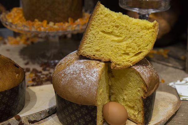 Panettone uova e altri ingredienti su un tavolo rustico