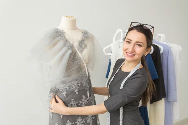 Una giovane donna sorridente in piedi contro un muro mostra un vestito su un manichino