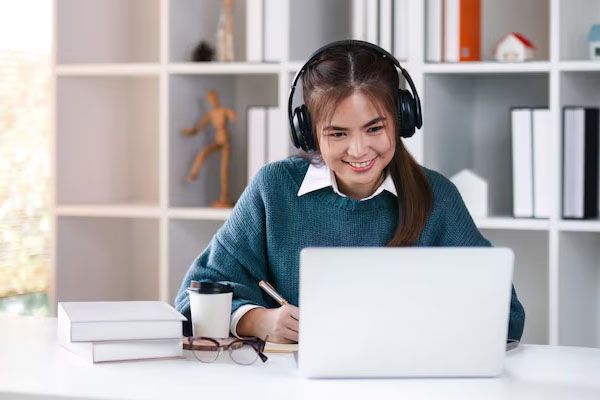Studentessa asiatica sorridente che guarda il computer