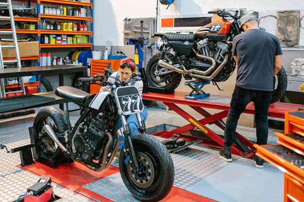 coppia di meccanici che riparano motociclette personalizzate in fabbrica