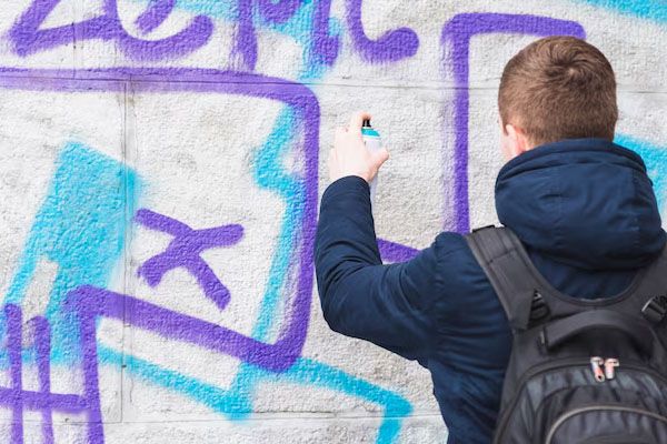 Vista posteriore di un uomo che disegna graffiti su un muro
