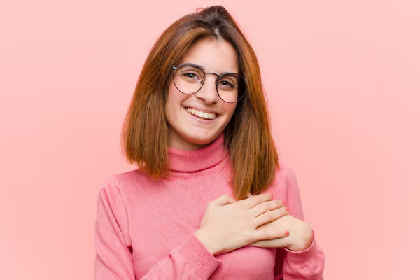 Una giovane donna sorridente si mette una mano sul petto