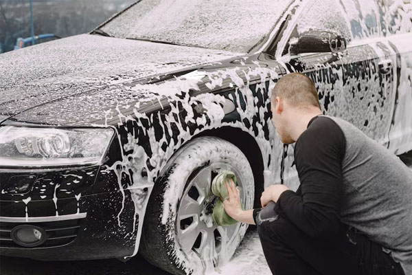 Uomo che lava a mano uno pneumatico per auto