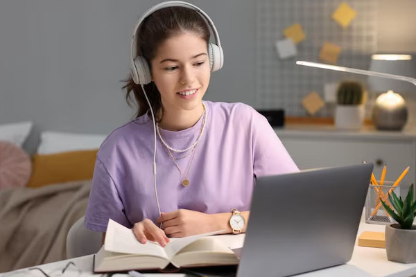 Giovane donna seduta alla scrivania davanti al computer portatile