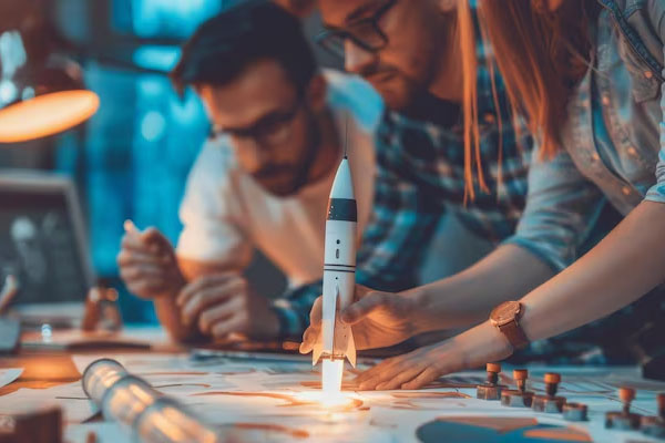 Modello di razzo in miniatura che decolla mentre le persone lavorano alla scrivania