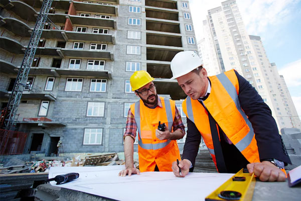 gruppo di persone in abiti da lavoro che guardano i progetti di costruzione