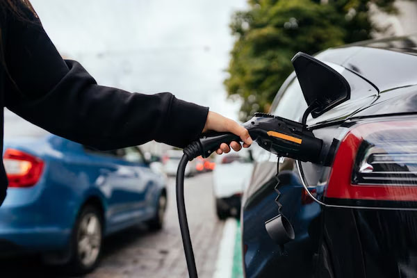 Primo piano di una mano che inserisce un caricabatterie su un'auto elettrica