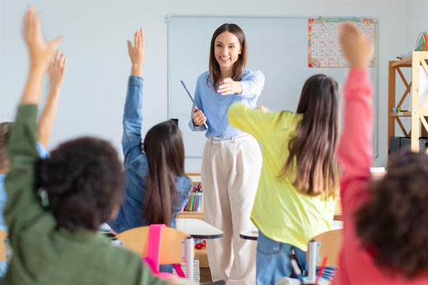 Un'insegnante in classe con i suoi studenti che alzano la mano